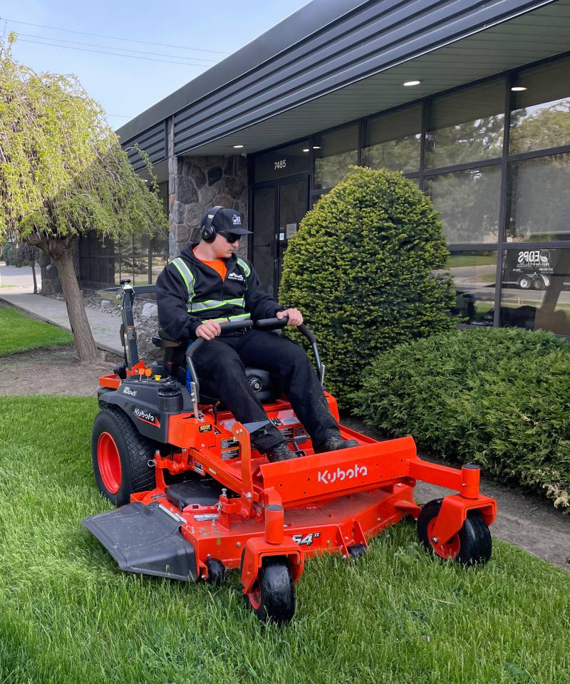 Operator sitting on a lawn mower performing lawn maintenance serices