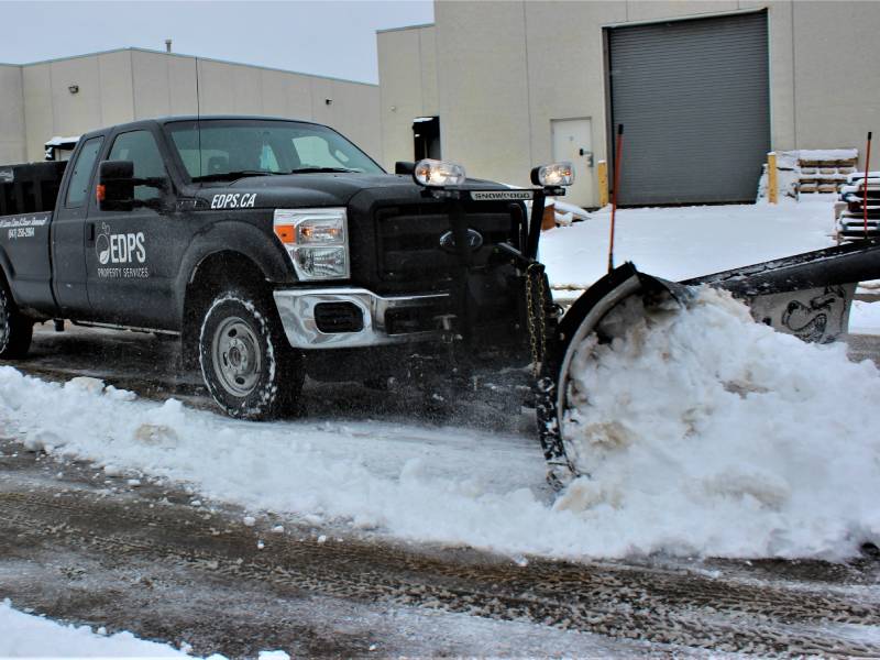 Snow plowing truck with v-blade