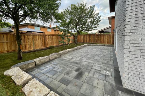 backyard interlocking patio and natural stone retaining wall in grey and black
